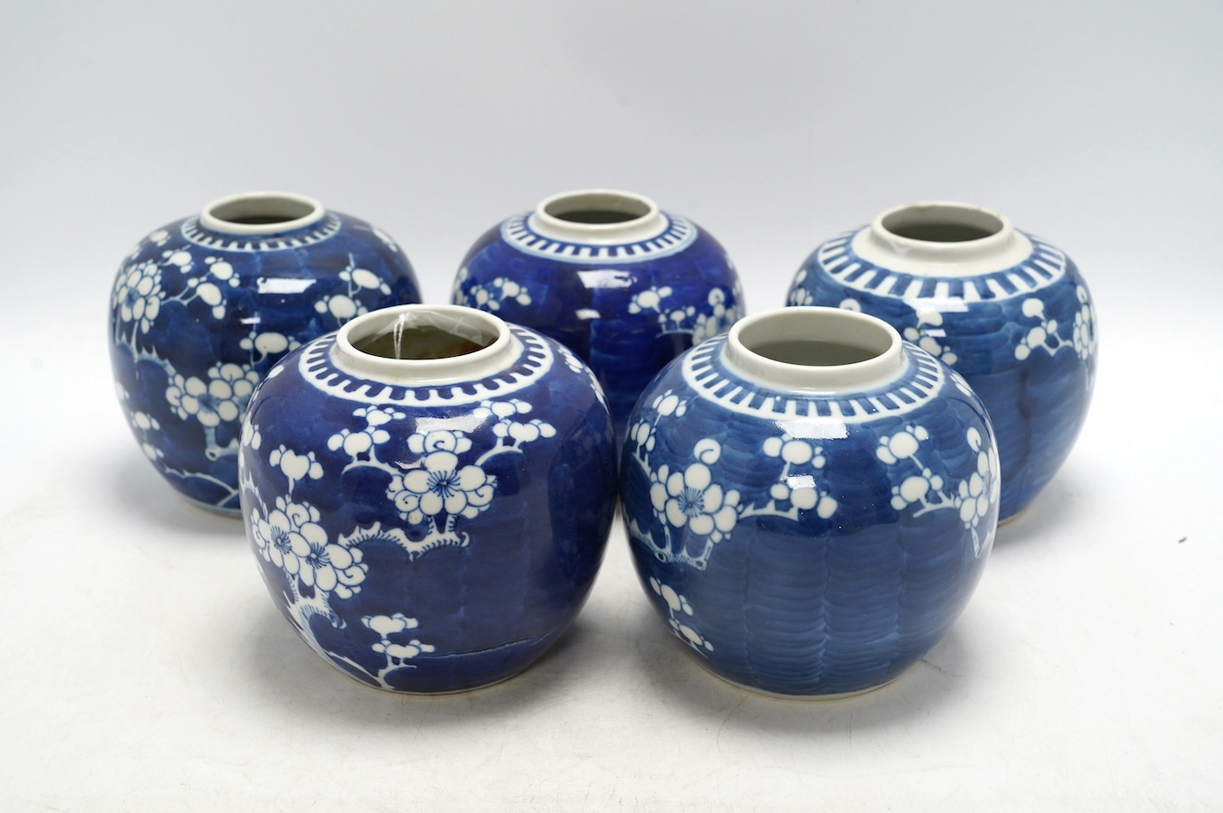 Five Chinese blue and white prunus jars, without covers, early 20th century, tallest 13cm high. Condition - one jar is chipped around the top, another has a large firing fault, the other two good